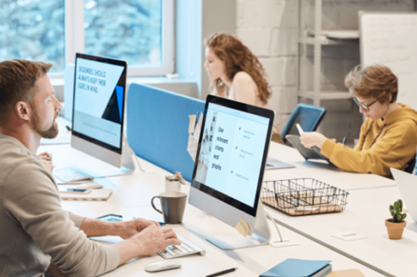 A diverse group of professionals collaborating at computers in a modern office environment.